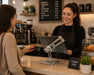 Cafe customer presenting a payment card while an employee uses a tablet mounted on an Agoz POS stand.