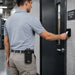 Field operations worker using an access card reader while wearing the black Agoz Sonim communication terminal case with snap closure on the front hip.