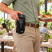 A person in a restaurant holding a plate of food while wearing a black Adyen POS handheld clipped to their belt.