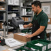 Employee printing pickup labels from a Brother label printer mounted beside an order fulfillment workstation.