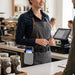 Hospitality worker wearing an AgozTech gray waist belt holster with Newland POS terminal at a service counter.