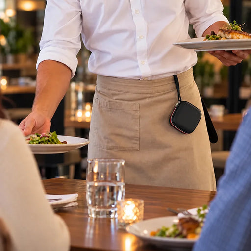 Restaurant server wearing a black Agoz Clover Go carrying case attached to an apron while serving meals, demonstrating convenient hands-free storage during service.