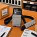 Gray Honeywell shoulder sling holster on a warehouse workstation with Honeywell handheld computer, pick list, barcode labels, and packing supplies.