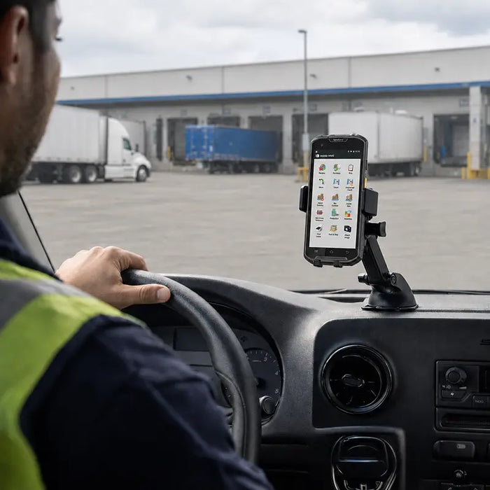 Newland mobile computer mounted on a dashboard cradle inside a delivery vehicle at an outdoor loading dock.