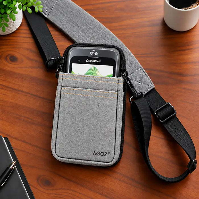 Gray Agoz rugged Orderman POS holster with payment terminal and adjustable crossbody sling featuring a padded shoulder section on a wooden desk.