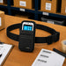 Black Panasonic Toughbook waist belt pouch displayed on a warehouse pick station with barcode labels, pick sheet, tape, and order processing materials.