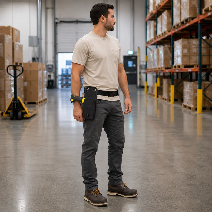 Worker wearing an Agoz Cognex DataMan 8700 waist belt holster scans barcode labels on wooden crates during loading dock audit and verification tasks.