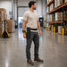 Worker wearing an Agoz Cognex DataMan 8700 waist belt holster scans barcode labels on wooden crates during loading dock audit and verification tasks.