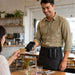 Restaurant server using a Toast Go 3 payment terminal while wearing an AgozTech leather case on a waist apron.