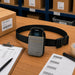 AGOZ gray waist case holding a Zebra rugged scanner on a warehouse packing table with a pick list, barcode labels, and shipping supplies.