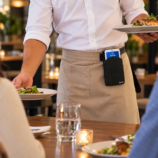 Restaurant server wearing the Agoz myPOS handheld case clipped to a belt while carrying plates, showing hands-free access during service.