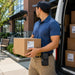 Delivery worker wearing the Urovo mobile computer case with belt clip while handling route packages from a service van.