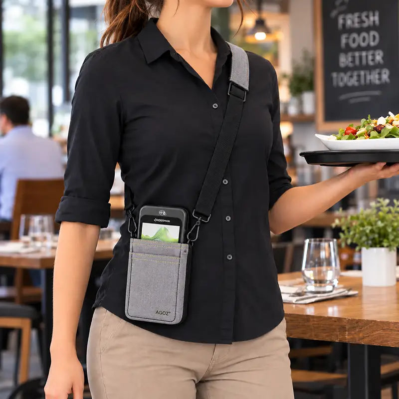 Restaurant server wearing gray Agoz Orderman POS holster with adjustable crossbody sling while carrying a food tray, keeping the payment terminal accessible.
