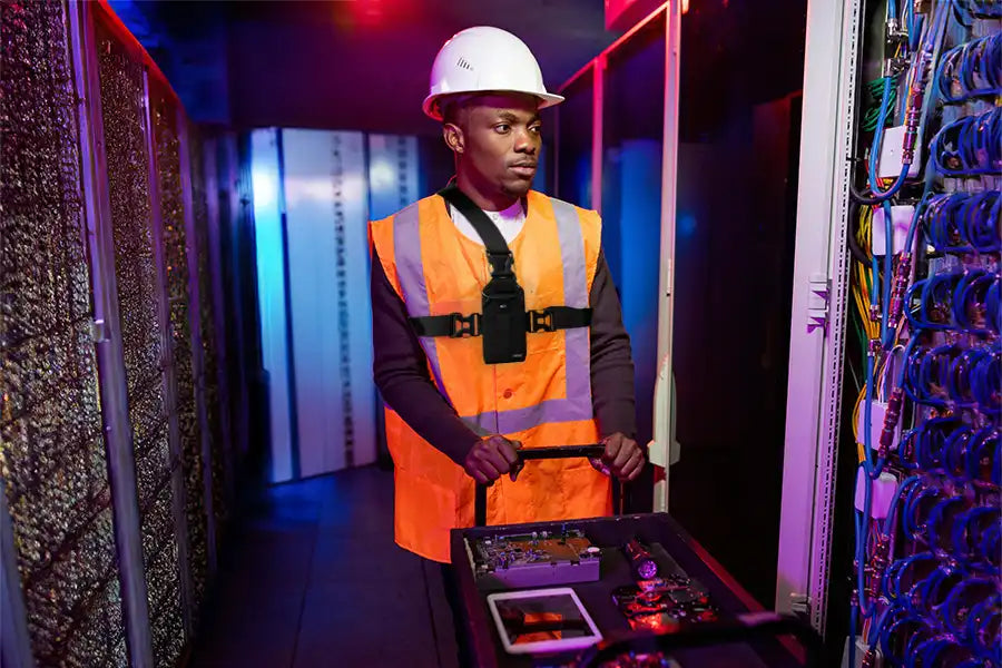 Field technician wearing Unication radio chest harness holster for hands-free access